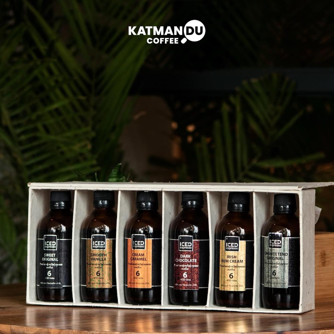 Box of Katmandu Coffee bottles with a blurred greenery background